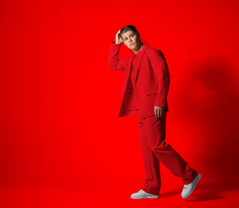 Man in rood pak voor een rode achtergrond